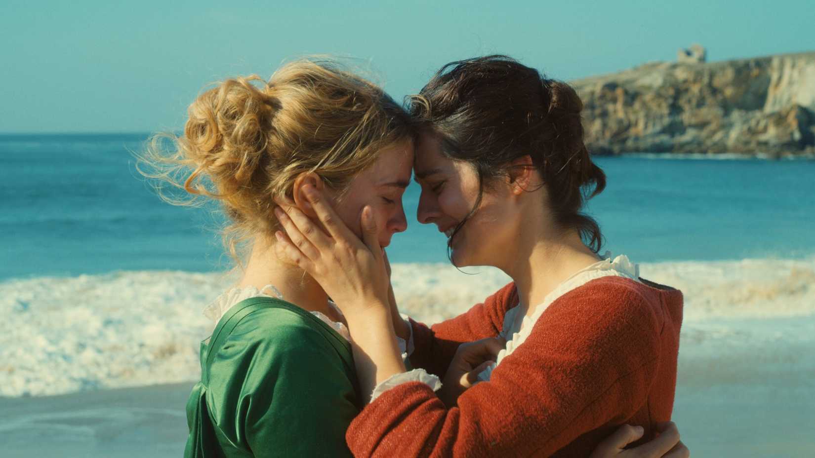 Duas mulheres se abraçam chorando na praia em Portrait of a Lady on Fire
