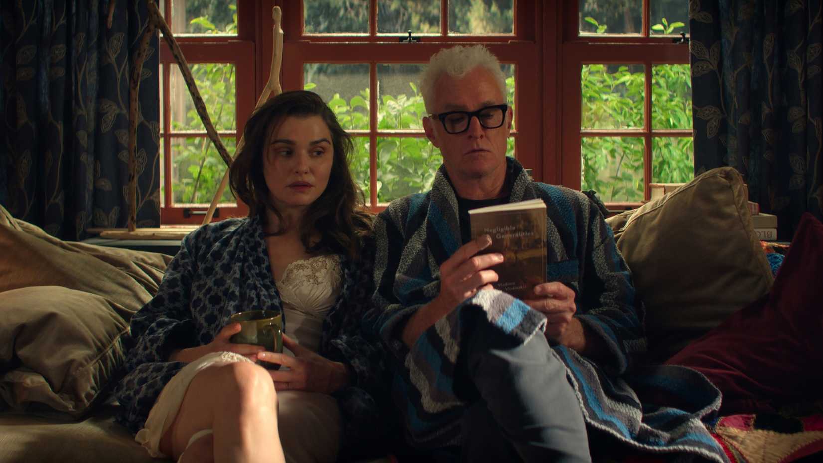 Rachel Weisz e John Slattery em um sofá em Vladimir