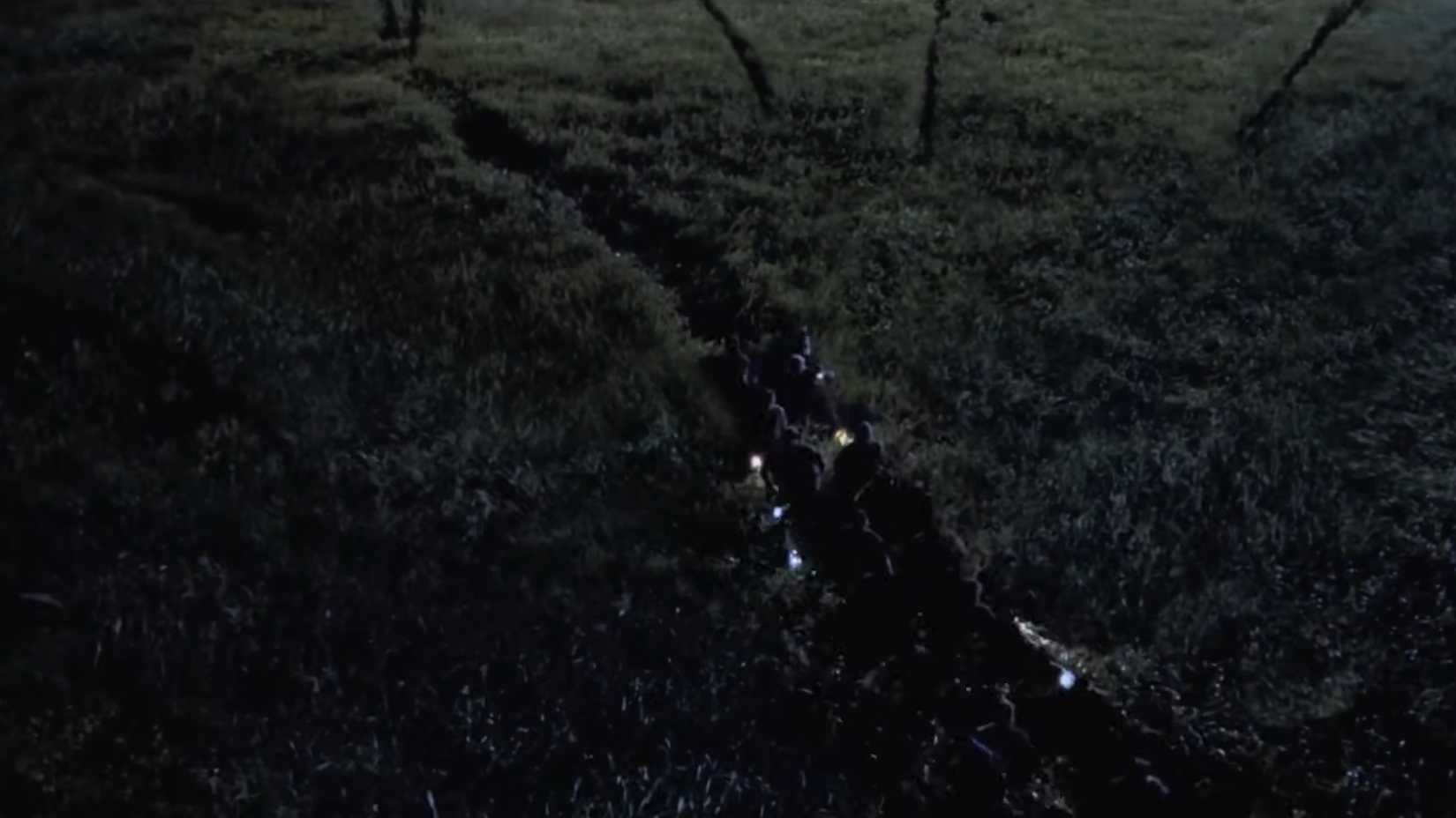 Velociraptors espreitando caçadores na grama alta em O Mundo Perdido: Jurassic Park