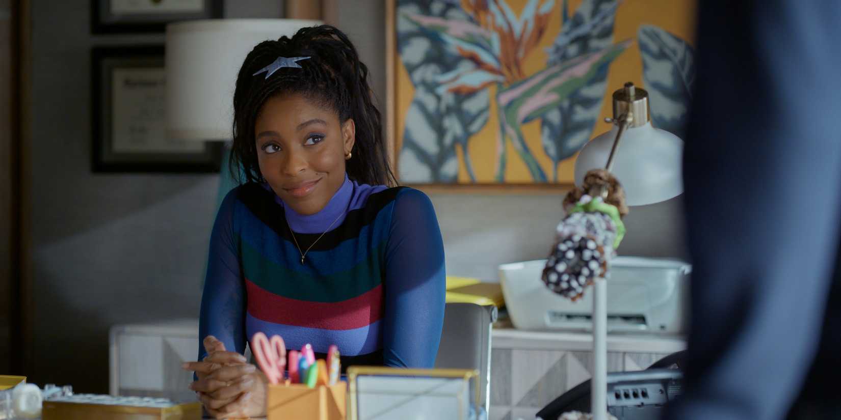 Gaby sitting at her desk and smiling in Shrinking season 3