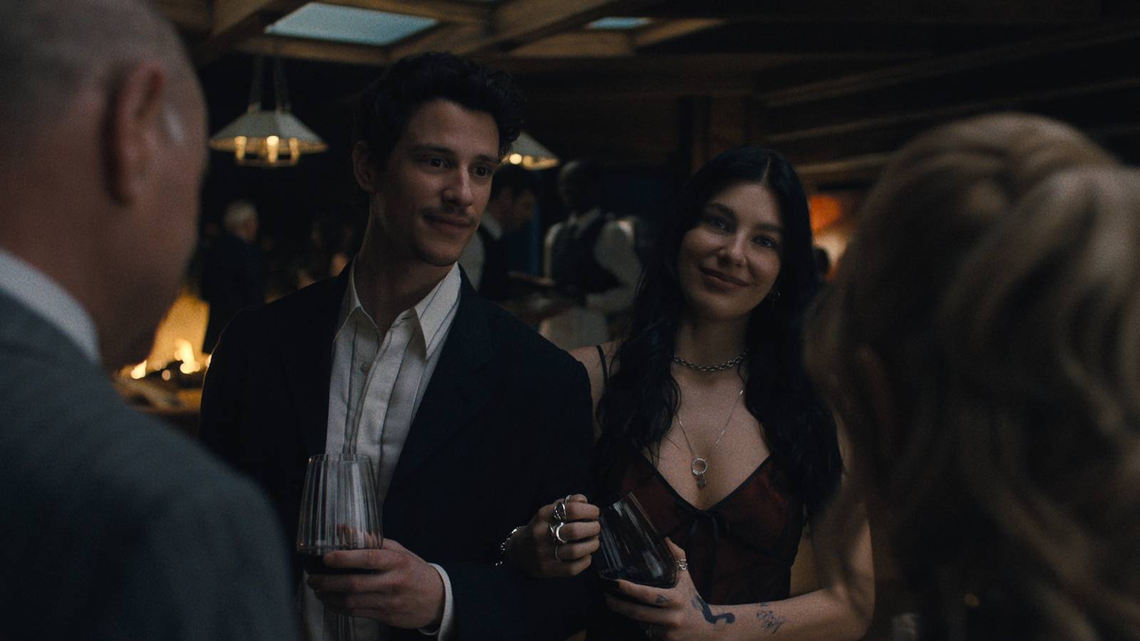 Rachel and Nicky stand together talking to an older couple at their rehearsal dinner in Something Very Bad Is Going to Happen.