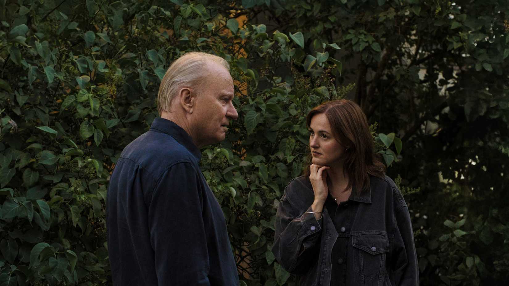 Stellan Skarsgard and Renate Reinsve have an awkward conversation by the bushes in Sentimental Value