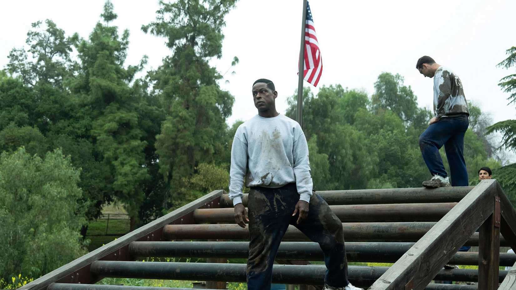 sterling k brown as xavier collins standing on an obstacle during military training with an american flag behind him in paradise
