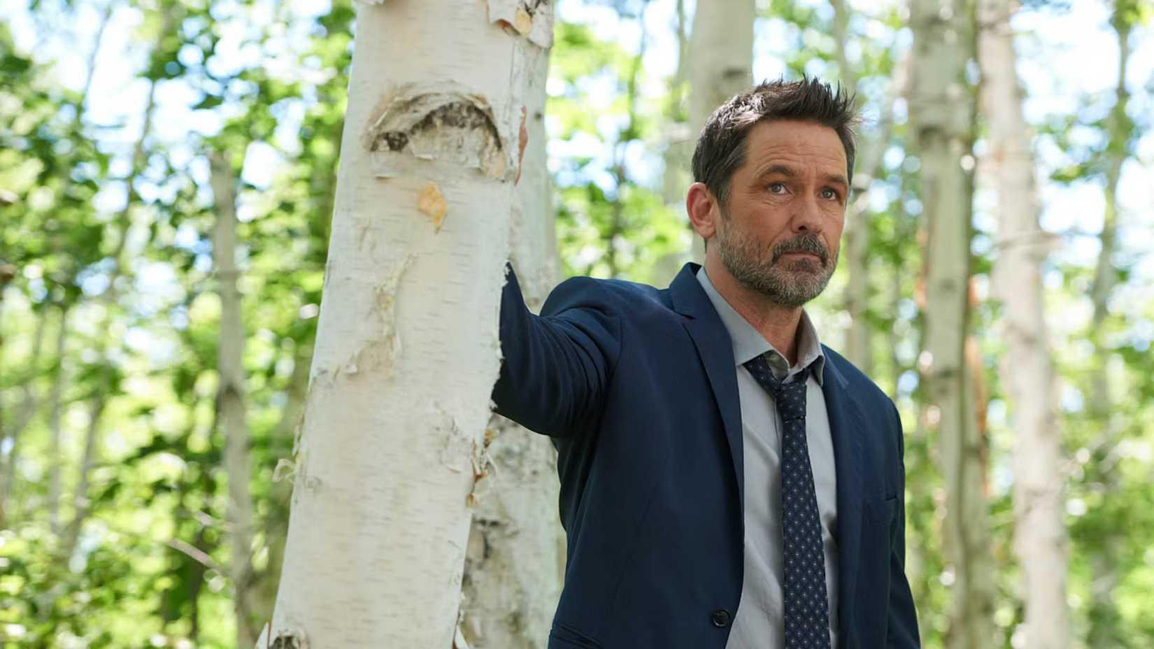 Cena de Cardinal com Billy Campbell como John Cardinal na floresta.