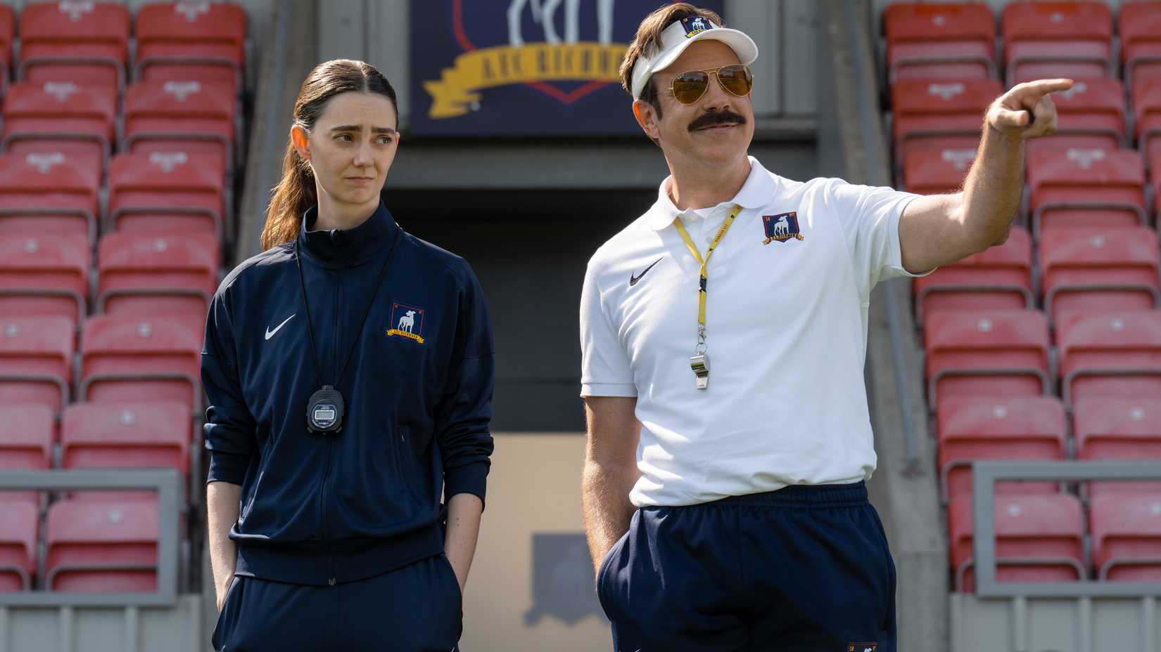 tanya reynolds looking doubtfully next to jason sudeikis ted pointing while smiling on the pitch in ted lasso season 4
