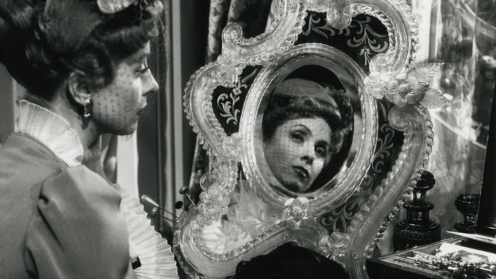 Uma mulher se olha no espelho em The Earrings of Madame de