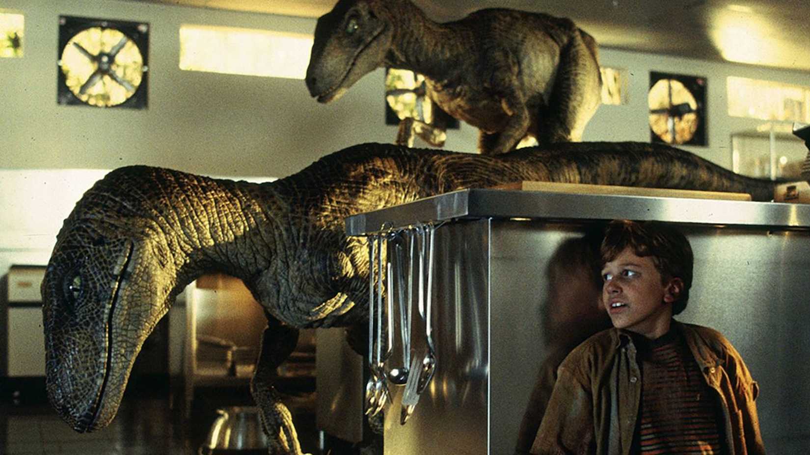 Tim se escondendo de dois raptors na cozinha em Jurassic Park