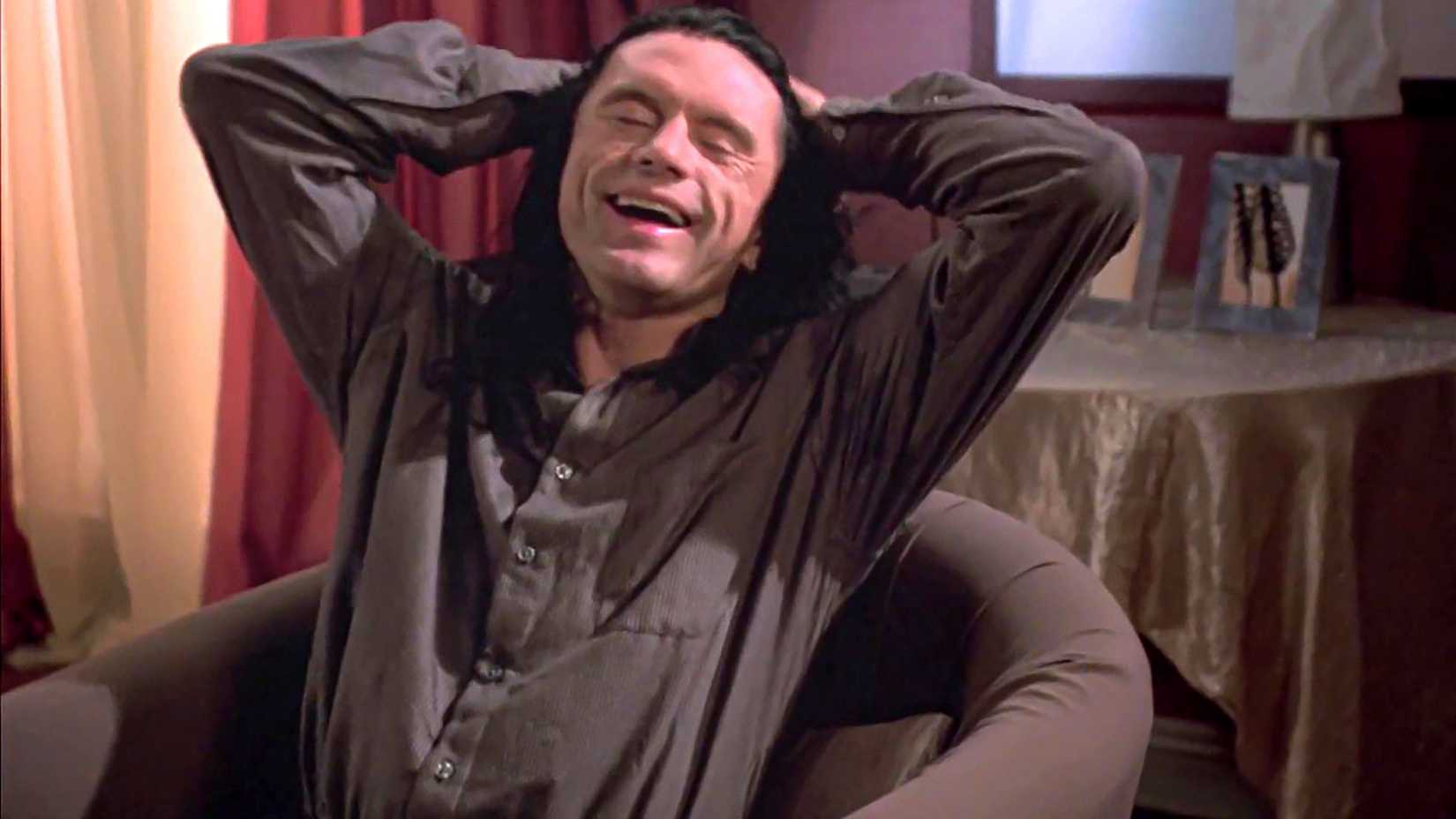 Tommy Wiseau's Johnny laughing while leaning back in a chair in The Room