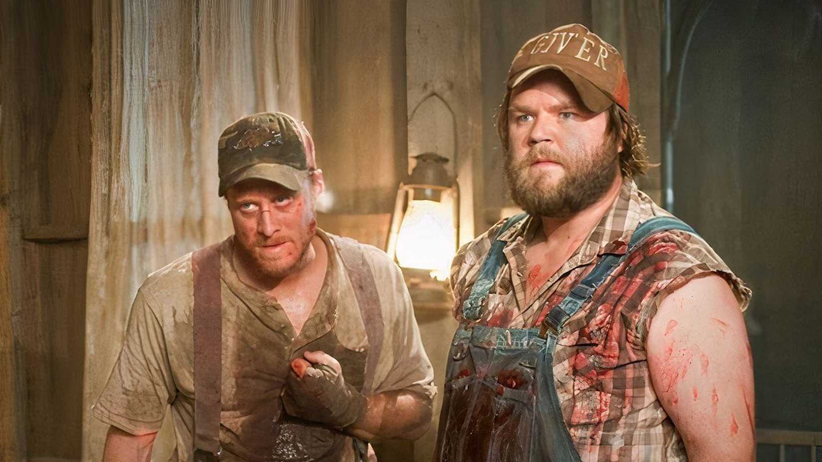 Tucker (Adam Tudyk) e Dale (Tyler Labine) em pé lado a lado com roupas ensanguentadas em Tucker & Dale Contra o Mal
