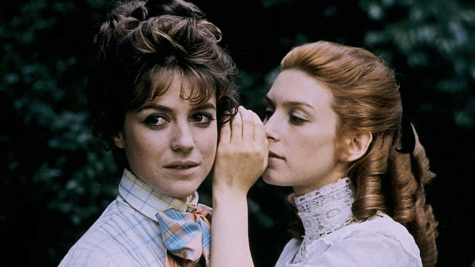 A woman whispers in another's ear in Two English Girls