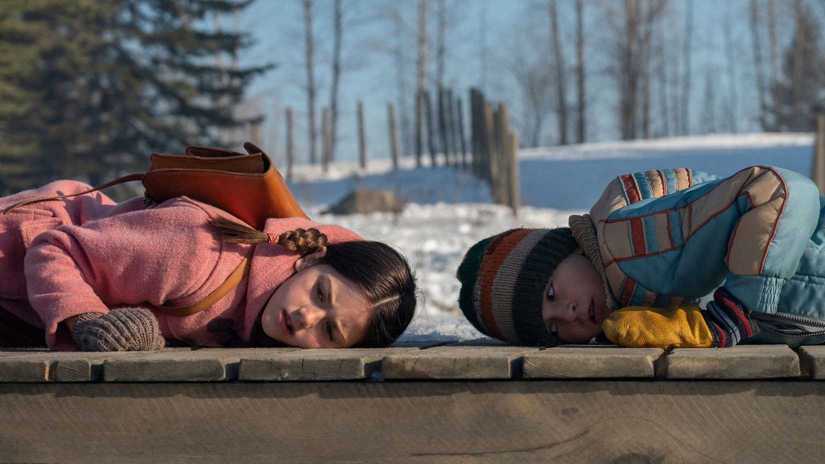 Two characters lying with their ears to the ground in Tales from the Loop