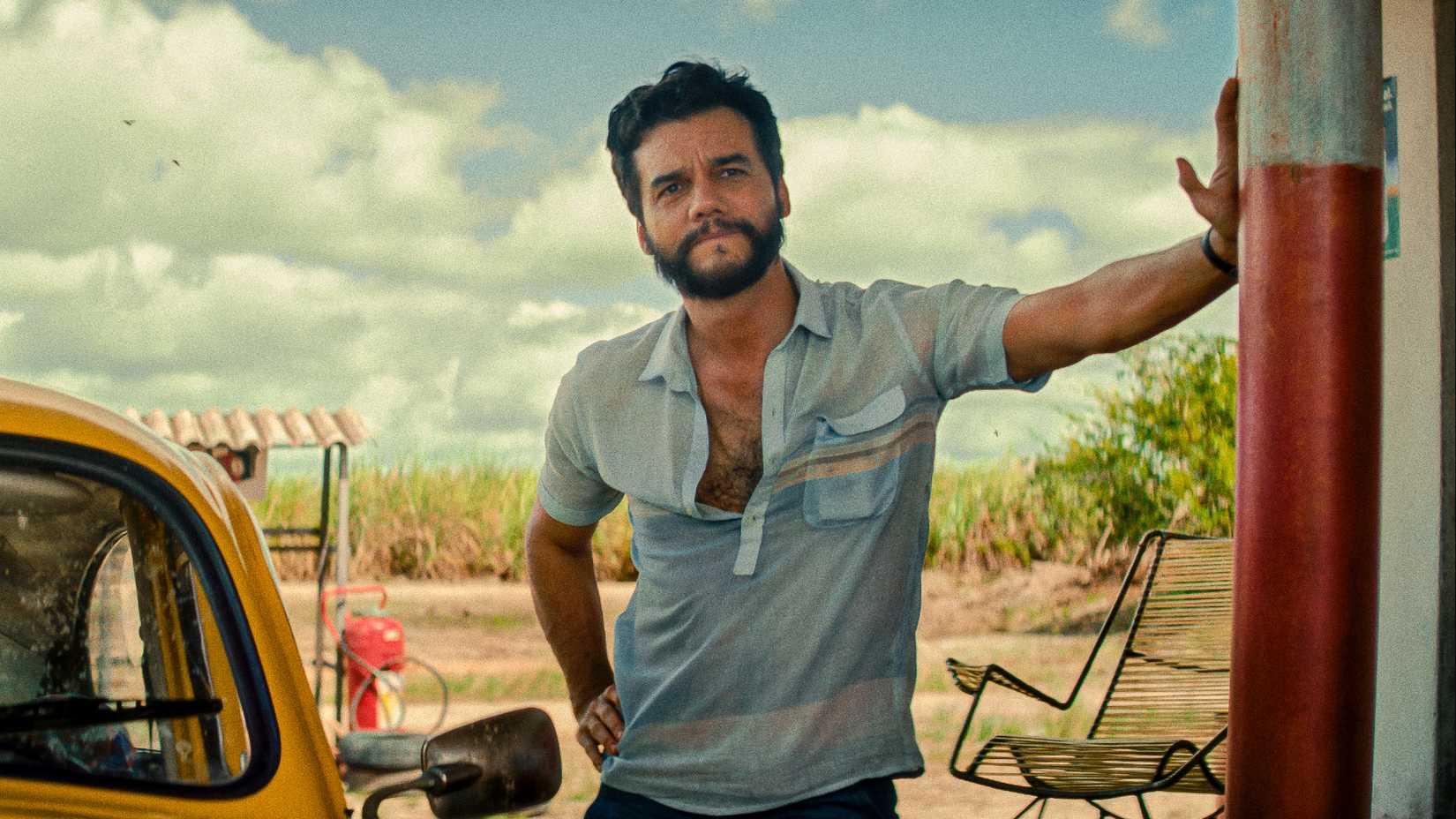 wagner moura stands next to his car at a gas station in the secret agent