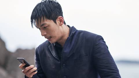 Wi Ha-jun as Hwang Jun-ho holding his phone in Squid Game