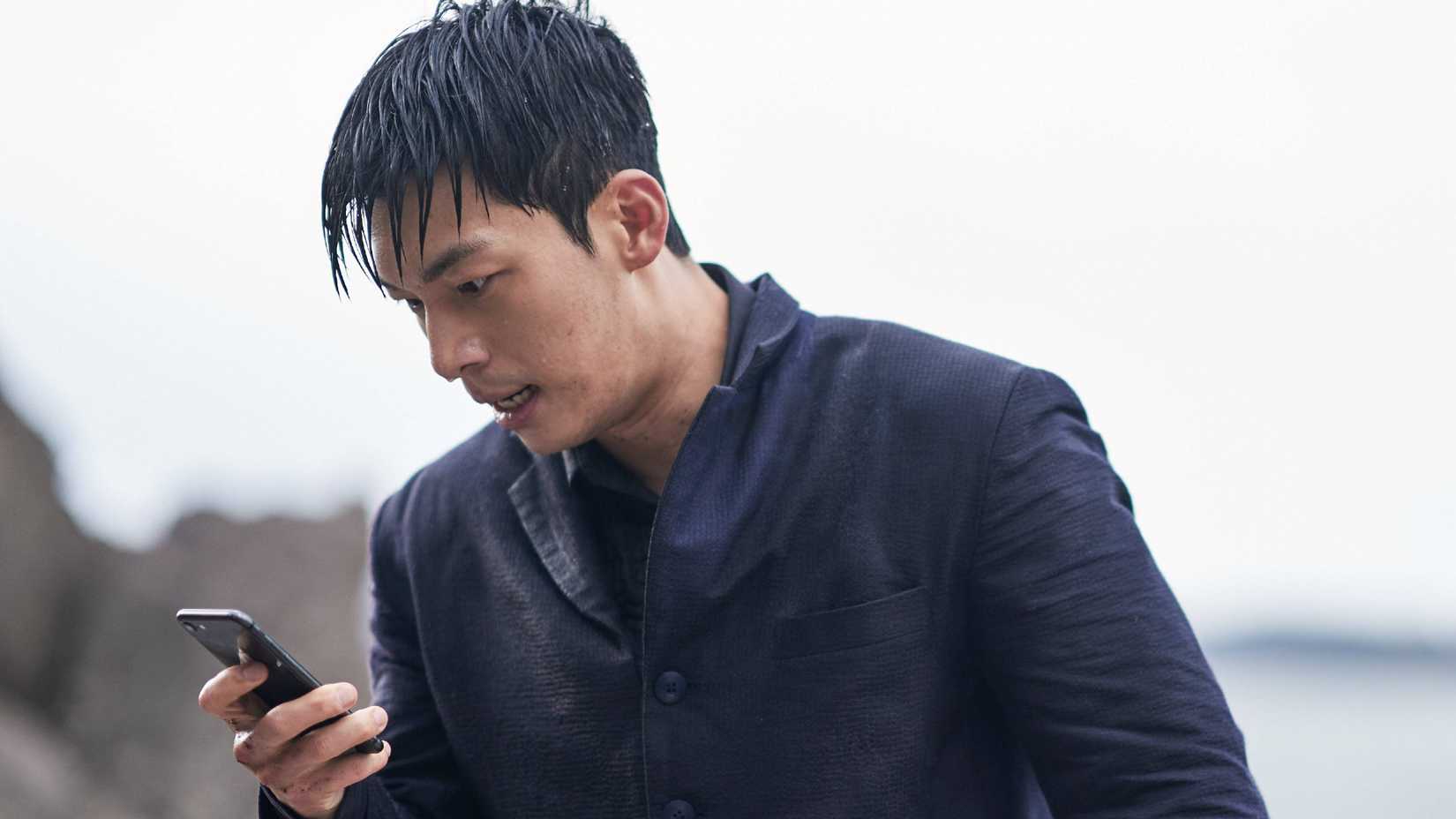 Wi Ha-jun as Hwang Jun-ho holding his phone in Squid Game