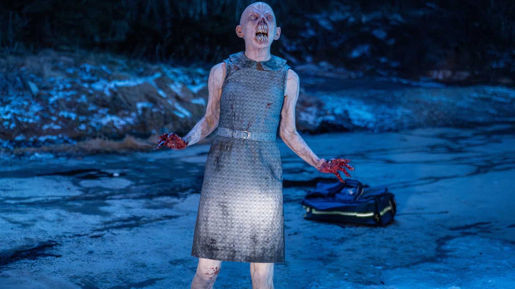 A monster in From with bloodied hands and screaming in the road at night