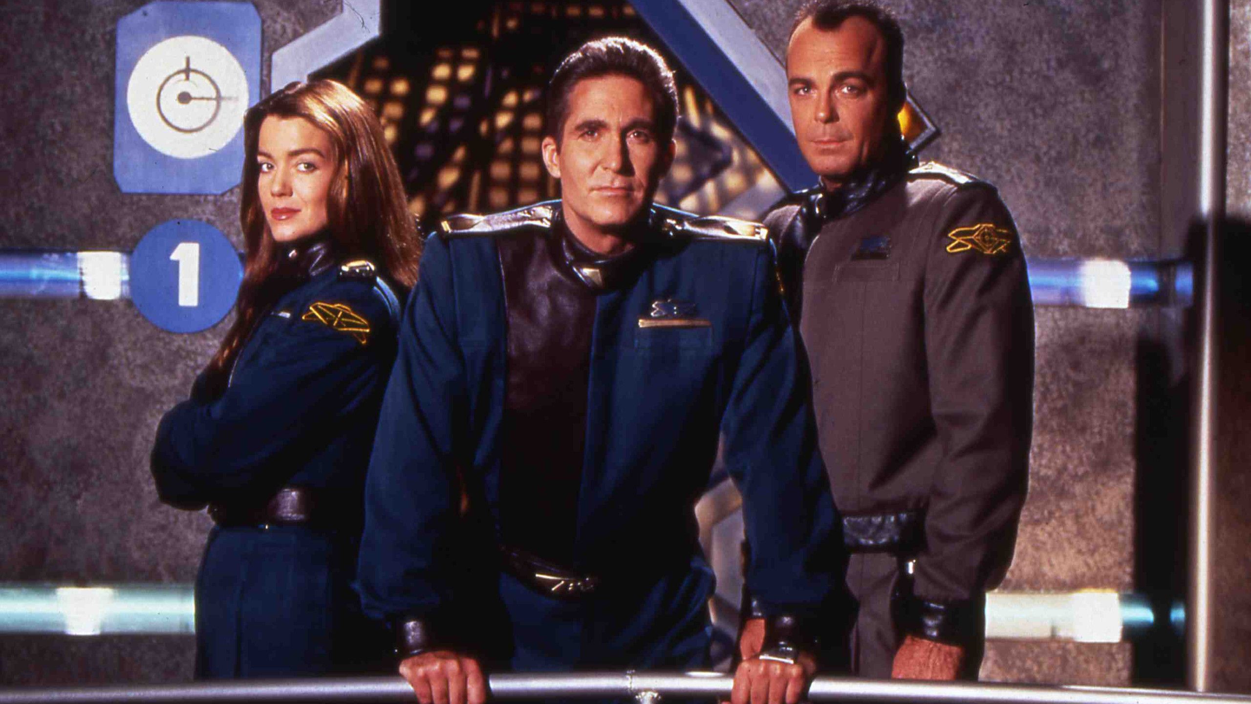 Babylon 5 still featuring Claudia Christian, Jerry Doyle, and Michael O'Hare posing on the balcony of the ship.