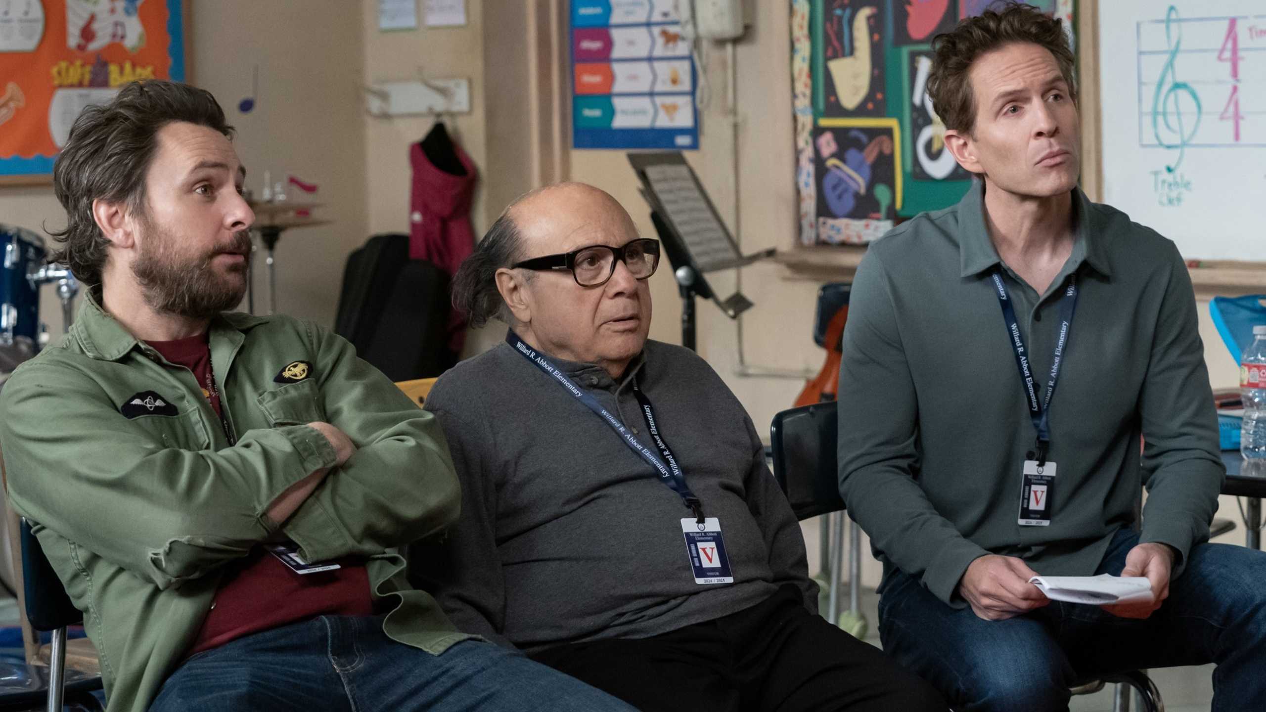 Charlie Day, Danny DeVito, Glenn Howerton wearing lanyards and sitting in Abbott Elementary