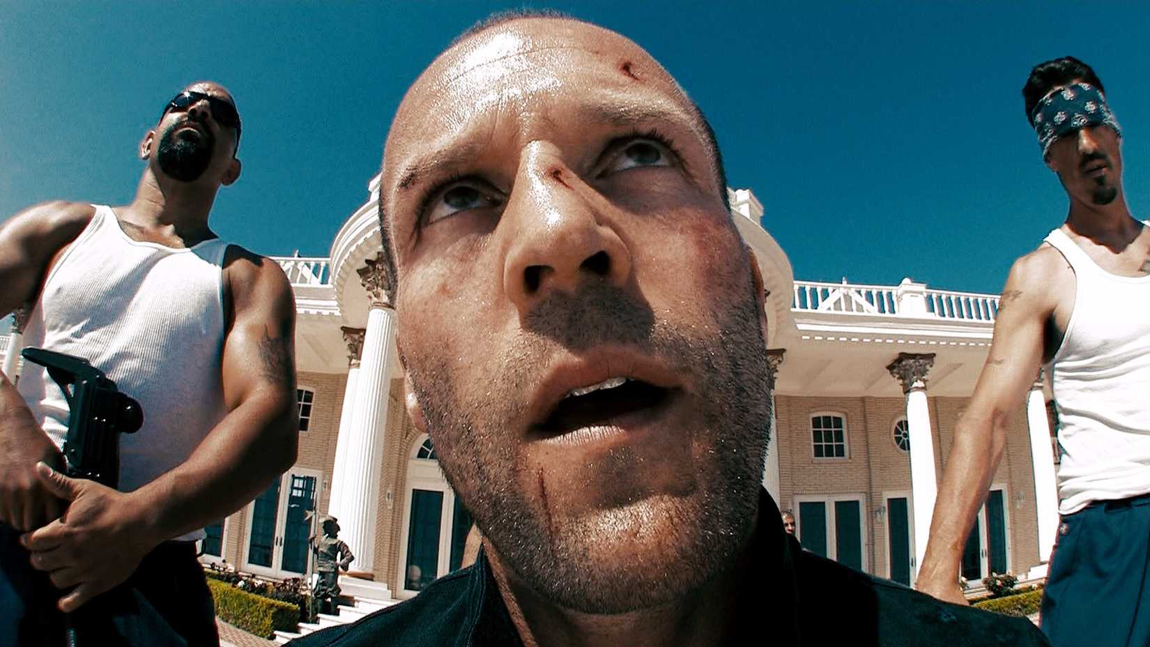 Chev (Jason Statham) with cuts on his face and guards to his sides in Crank-1