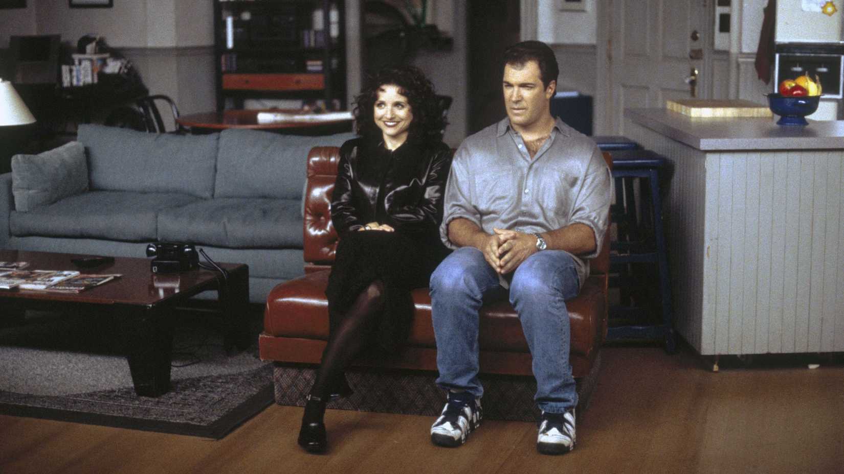Elaine (Julia Louis-Dreyfus) sentada ao lado de Dave Puddy (Patrick Warburton) em Seinfeld: A Concessionária.