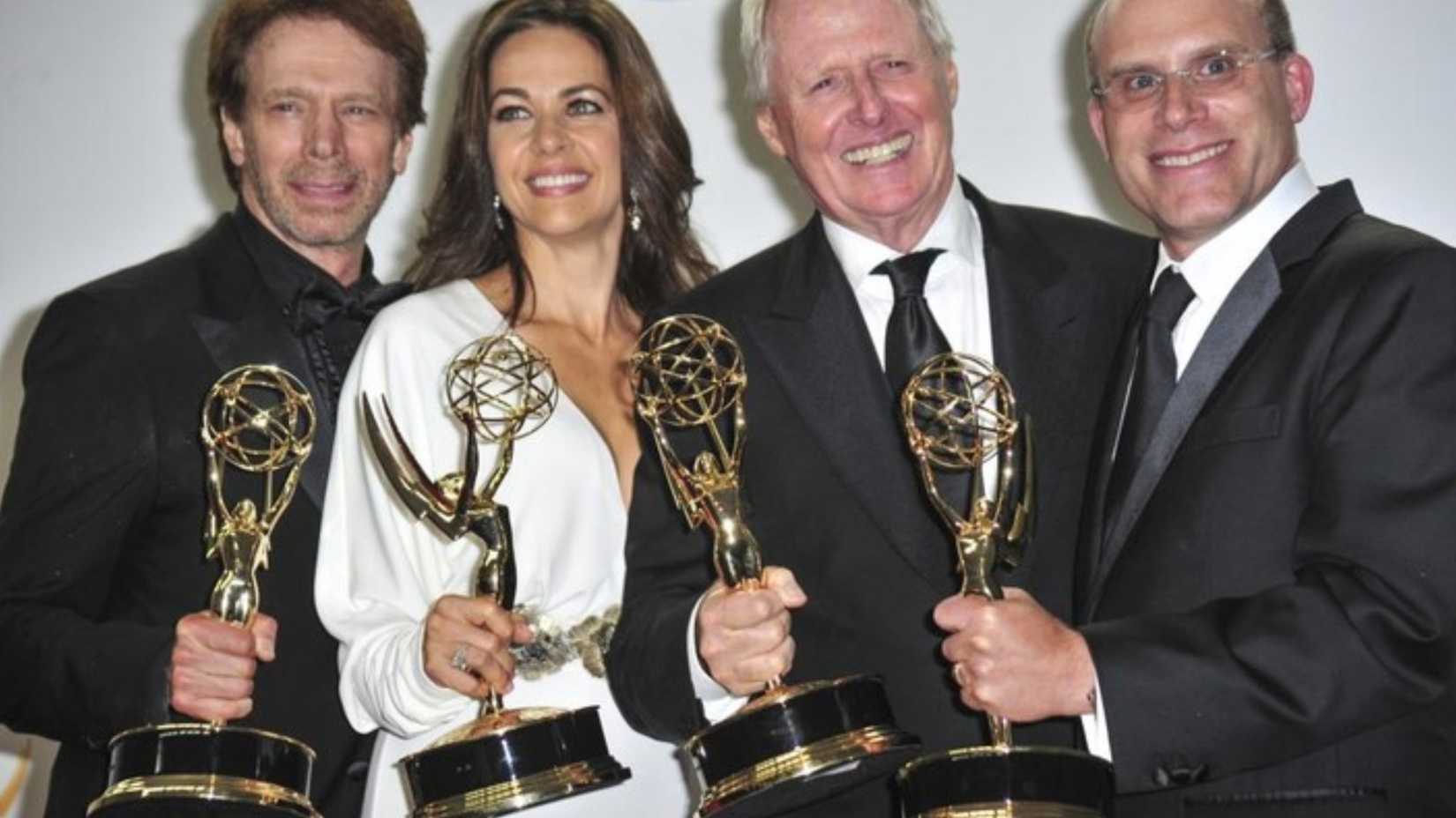 Elise Doganieri holding an Emmy Award with three men