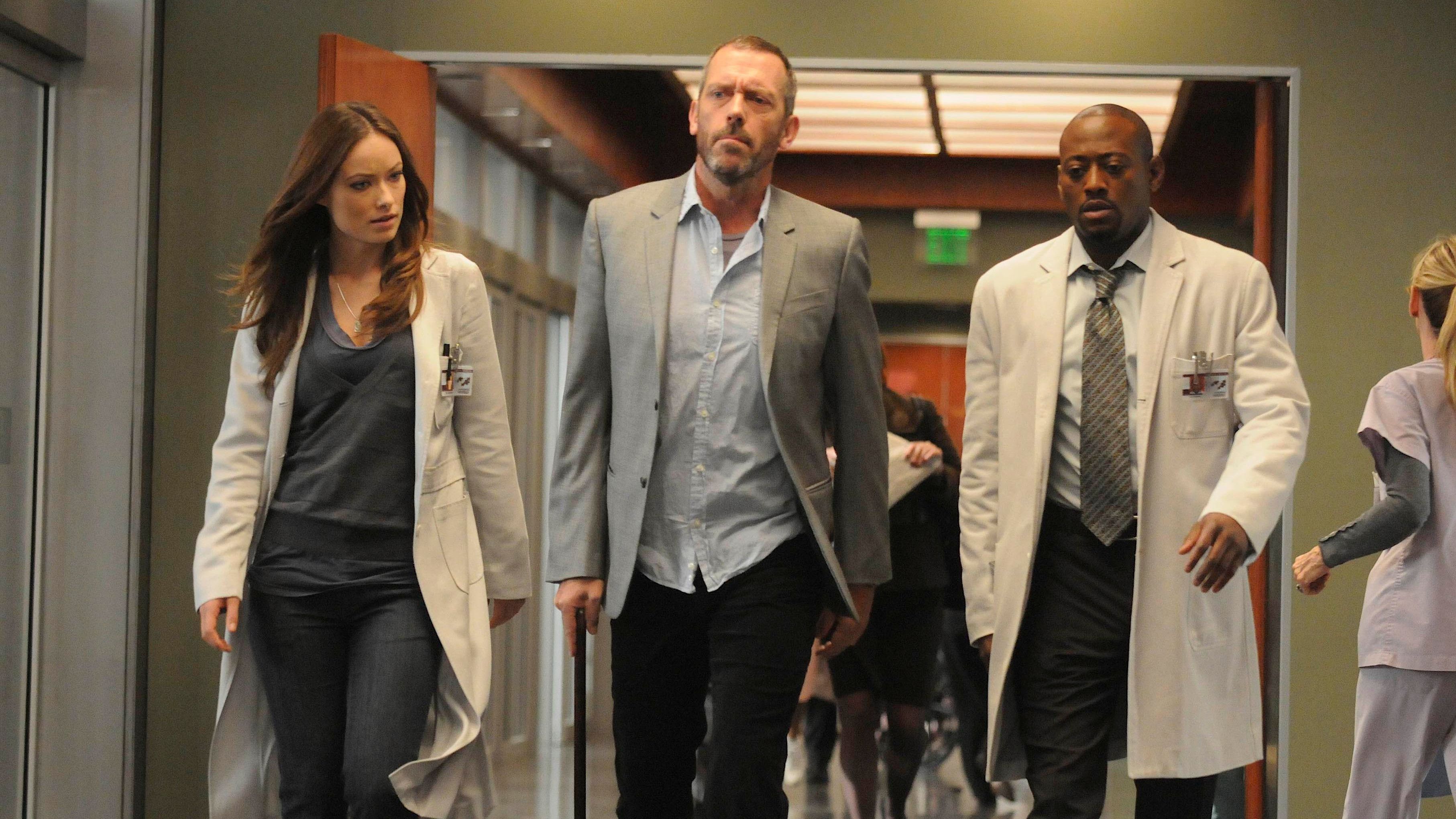 Gregory House doing a walk-and-talk with his cane flanked by Thirteen and Eric Foreman in House