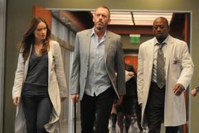 Gregory House doing a walk-and-talk with his cane flanked by Thirteen and Eric Foreman in House