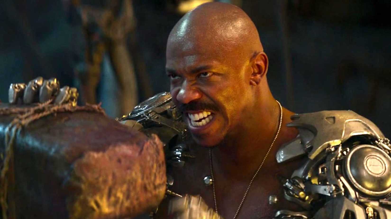 Jax com uma expressão de dor enquanto bloqueia um ataque de martelo em Mortal Kombat 2021