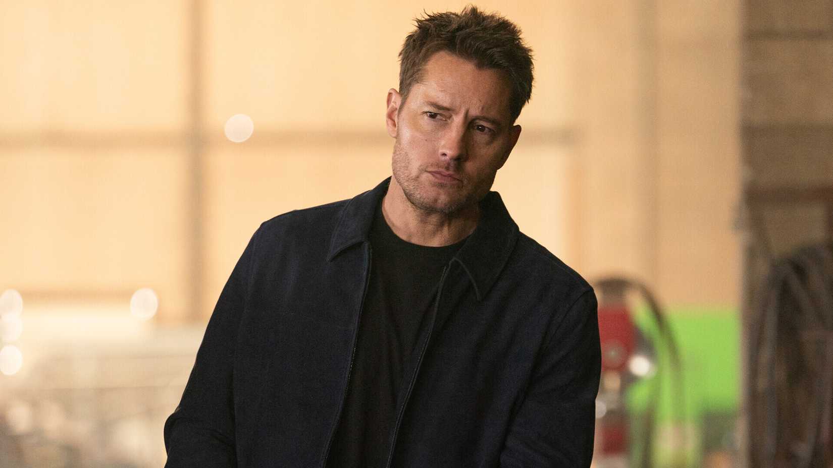 Justin Hartley as Colter Shaw walking in an episode of Tracker and carrying a gun
