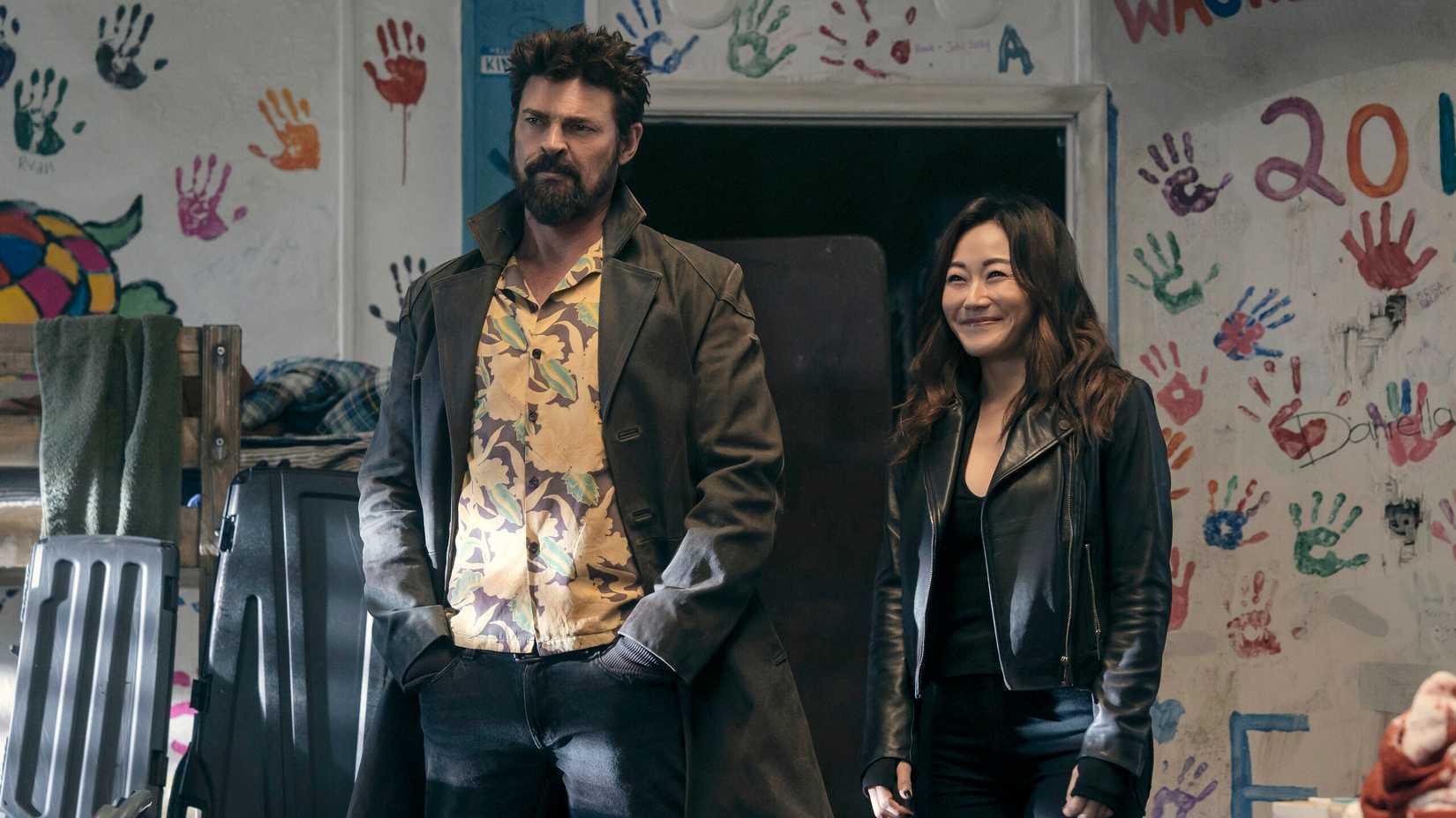 karl urban as butcher with his hands in his pocket next to karen fukuhara smiling widely as kimiko in the boys season 5