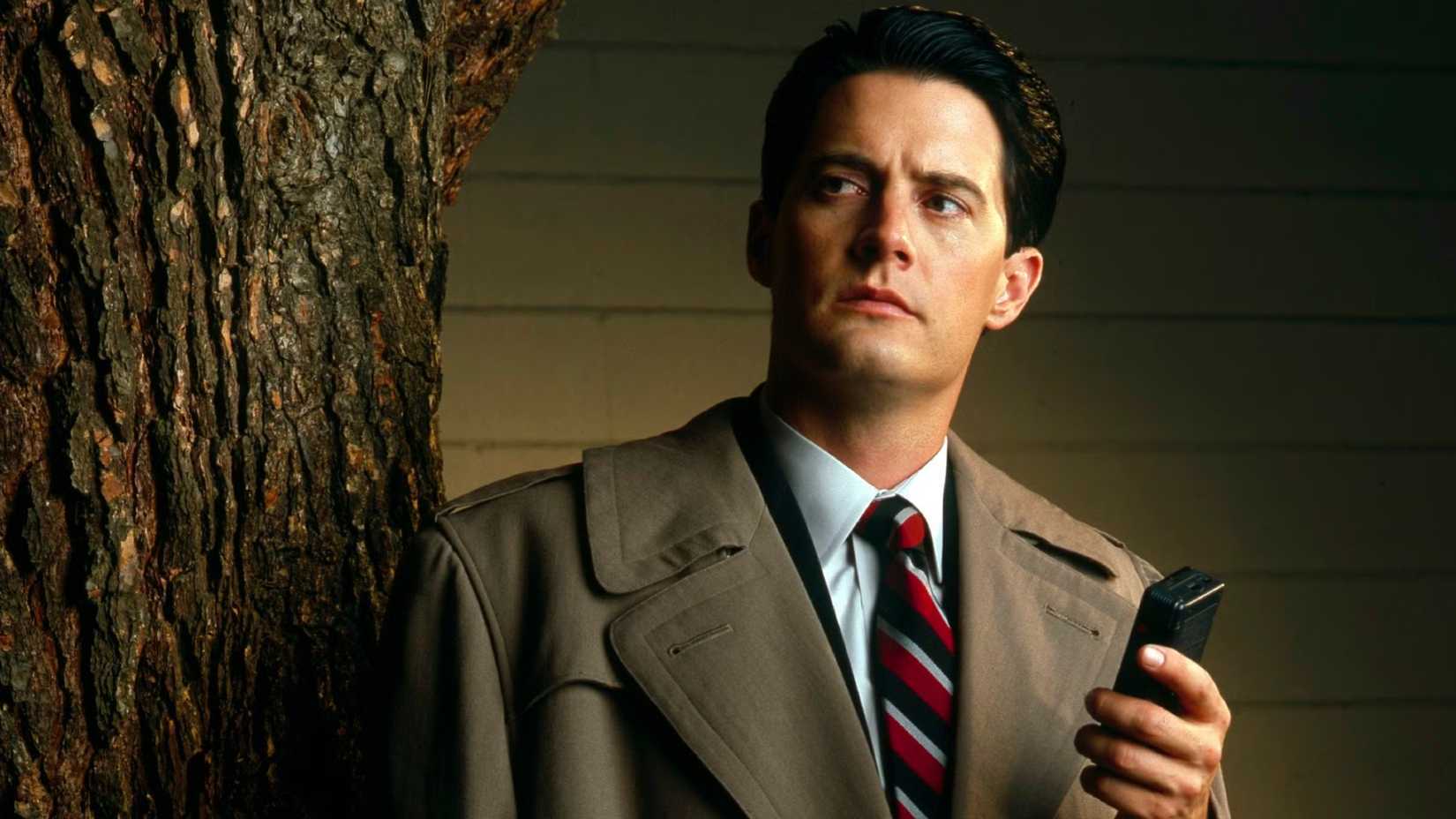 Kyle MacLachlan as Agent Dale Cooper holding up a recorder in a promo image for Twin Peaks