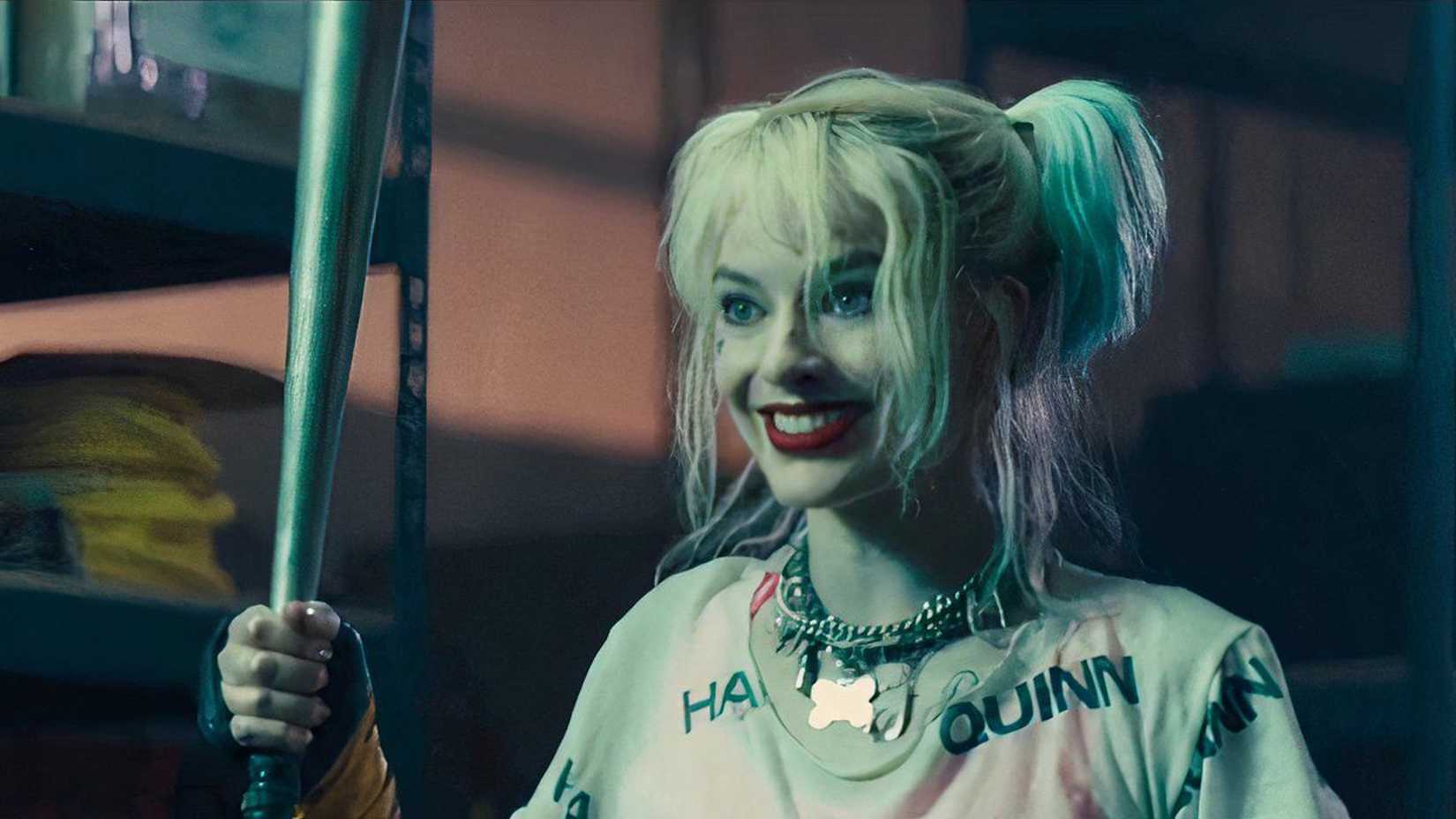 Margot Robbie como Arlequina sorrindo e segurando um taco em Aves de Rapina