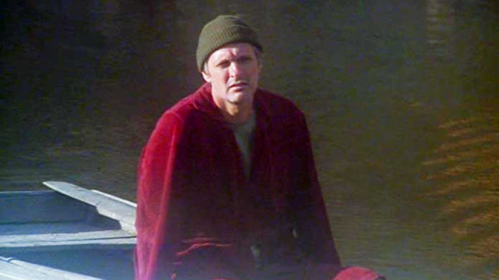 Alan Alda como Hawkeye sentado em um barco a remo em M*A*S*H