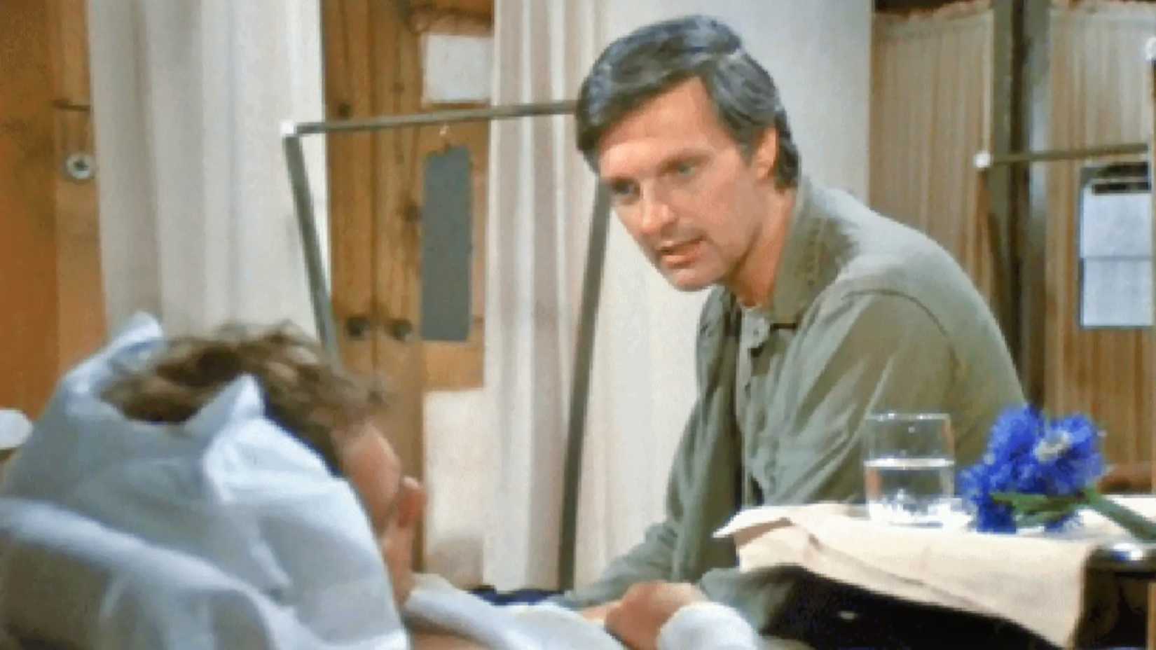 Hawkeye sentado na cama do hospital de Radar em M*A*S*H