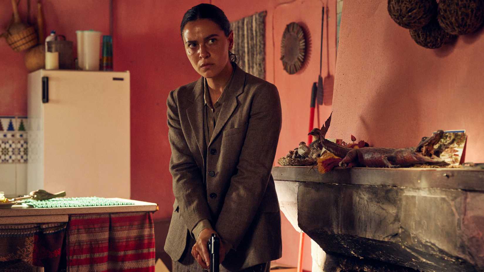 May Calamawy canvassing a red-walled room with her gun drawn in Lee Cronin's The Mummy