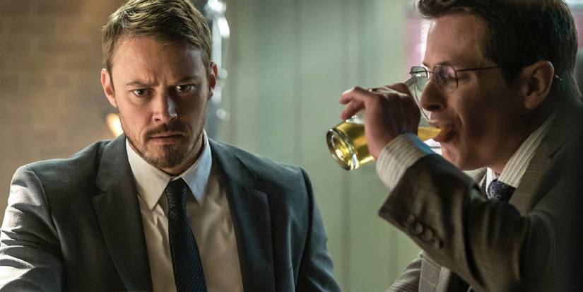 Michael Dorman com uma expressão confusa enquanto um homem ao lado dele bebe uma cerveja em Patriot