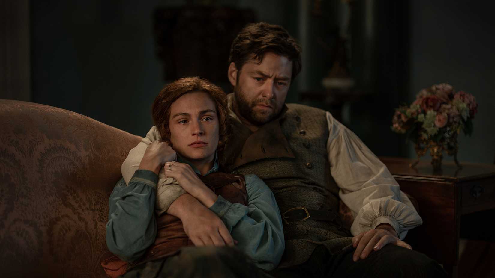 Roger and Brianna sitting together looking blackened and devastated in Outlander season 8