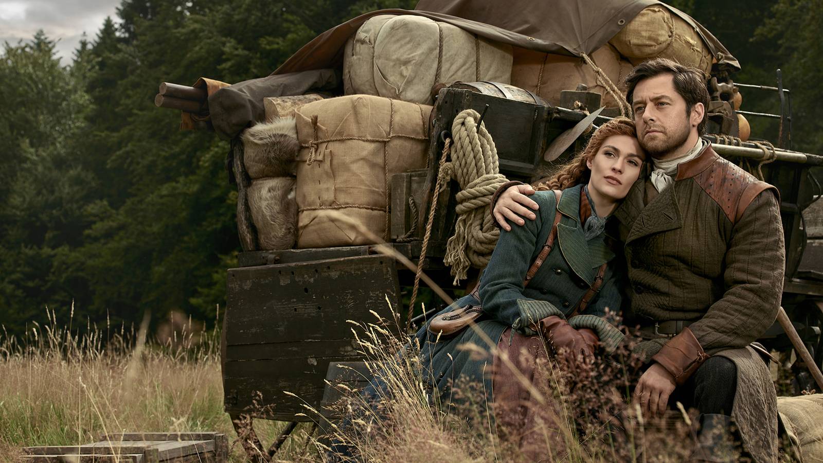 Brianna and Roger sitting together next to a cart in Outlander season 8