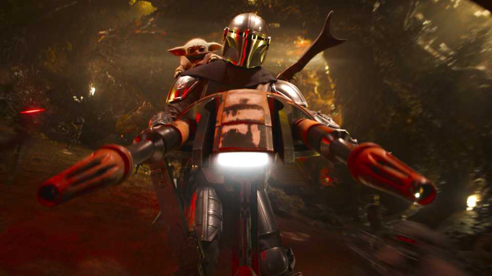 Pedro Pascal's Din Djarin and Grogu riding a speeder bike through a cave while getting shot at in The Mandalorian and Grogu
