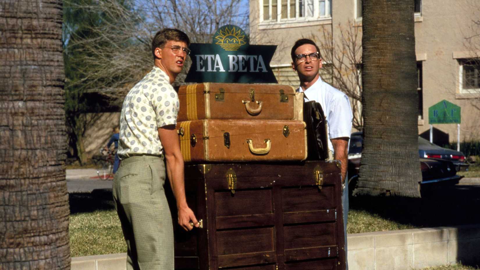 Two men carry large trunks in Revenge of the Nerds