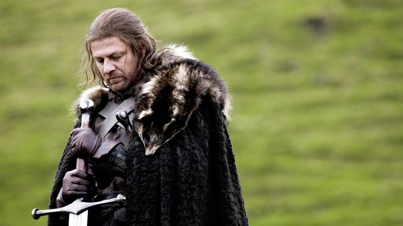 Sean Bean as Ned Stark holding a sword and looking down in Game of Thrones season 1, episode 1