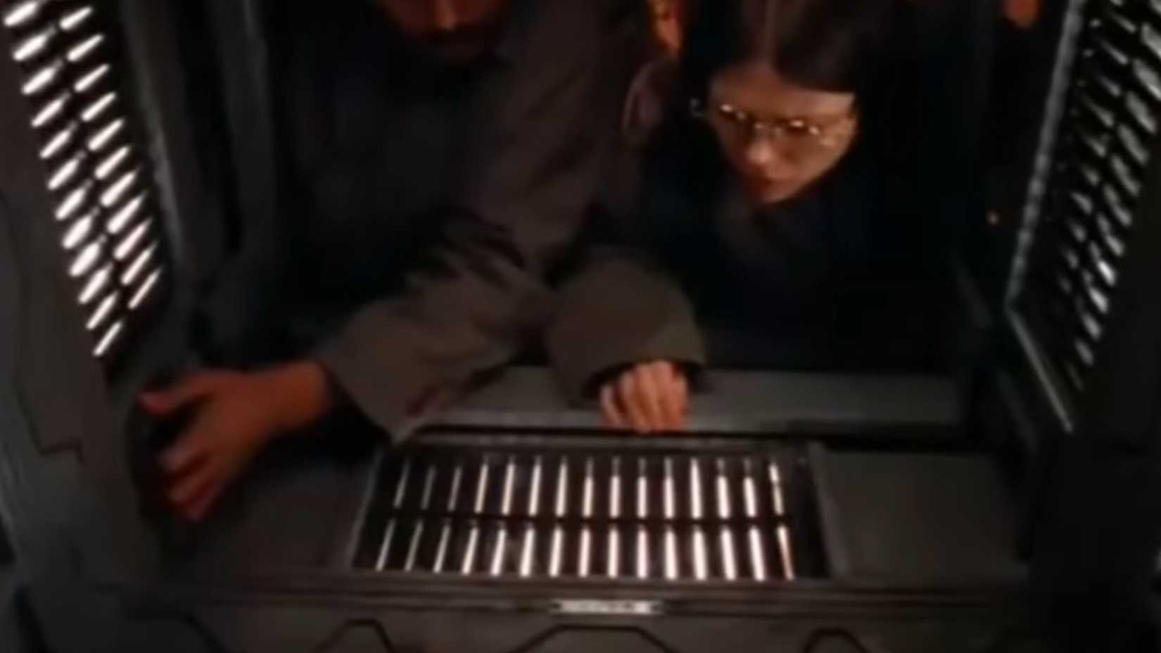 Sobreviventes navegando cuidadosamente por um corredor estreito em Cube 1997