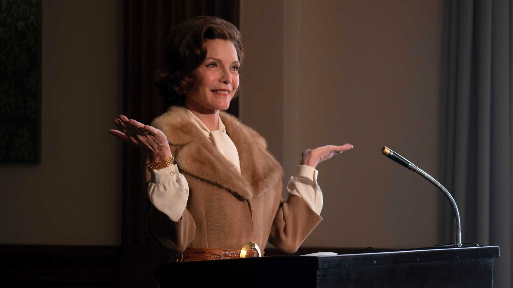 Betty Ford stands in front of a podium in the tv show The First Lady