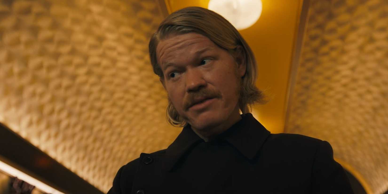 Jesse Plemons como Plutarch Heavensbee olhando para o lado em The Hunger Games: Sunrise on the Reaping.