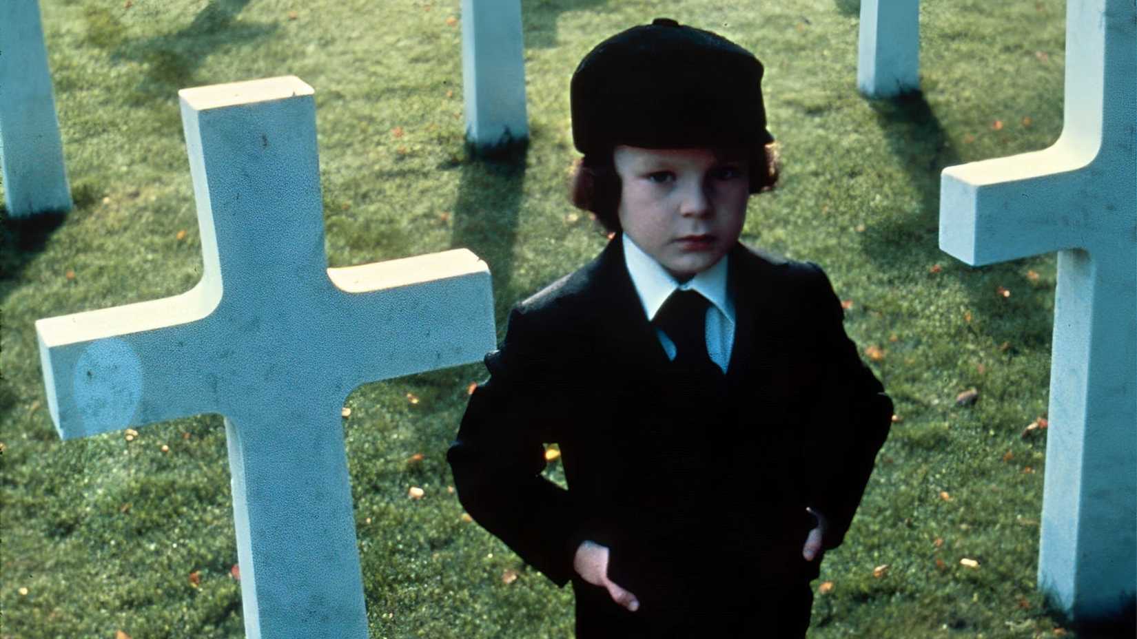 Damien stands among tombstones in The Omen