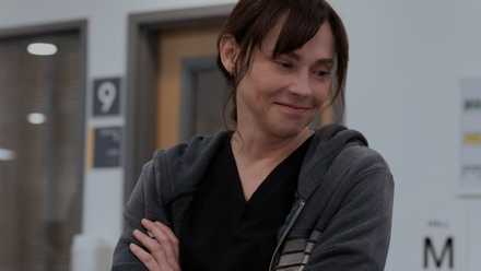 Fiona Dourif as Dr. Cassie McKay smiling with her arms folded in The Pitt.