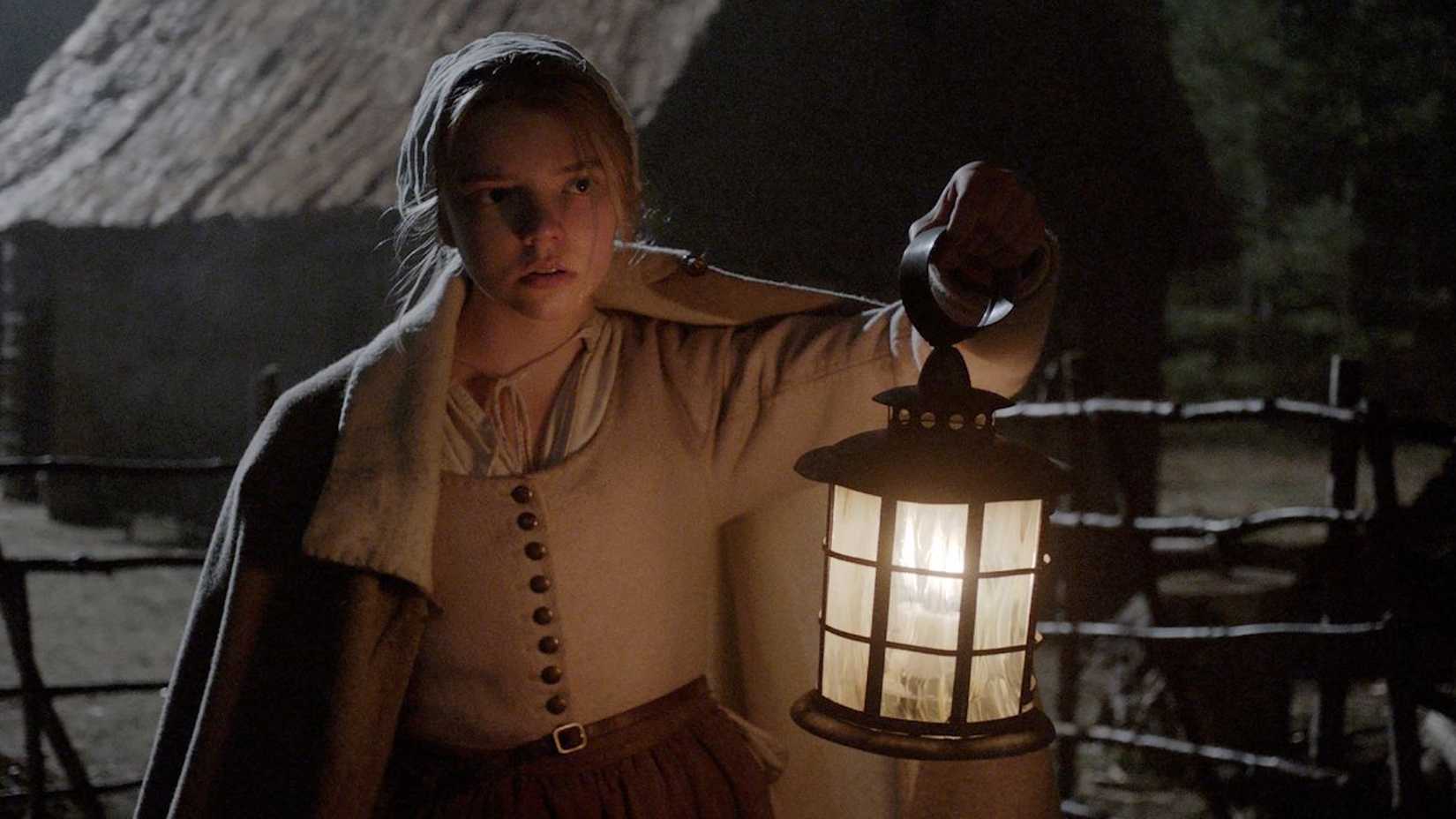 Thomasin holding up a lantern in the dark in The Witch