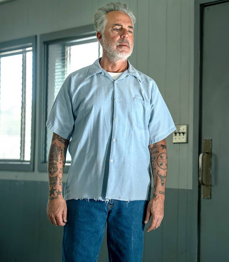 Titus Welliver's McNair standing confidently next to a prison guard in Dark Winds season 4 Vertical