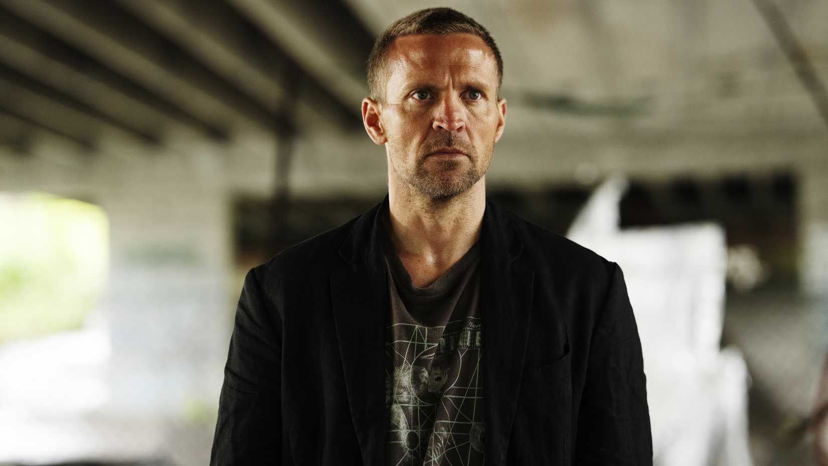 Tobias Santelmann's Harry looking in thought under an overpass in Detective Hole season 1
