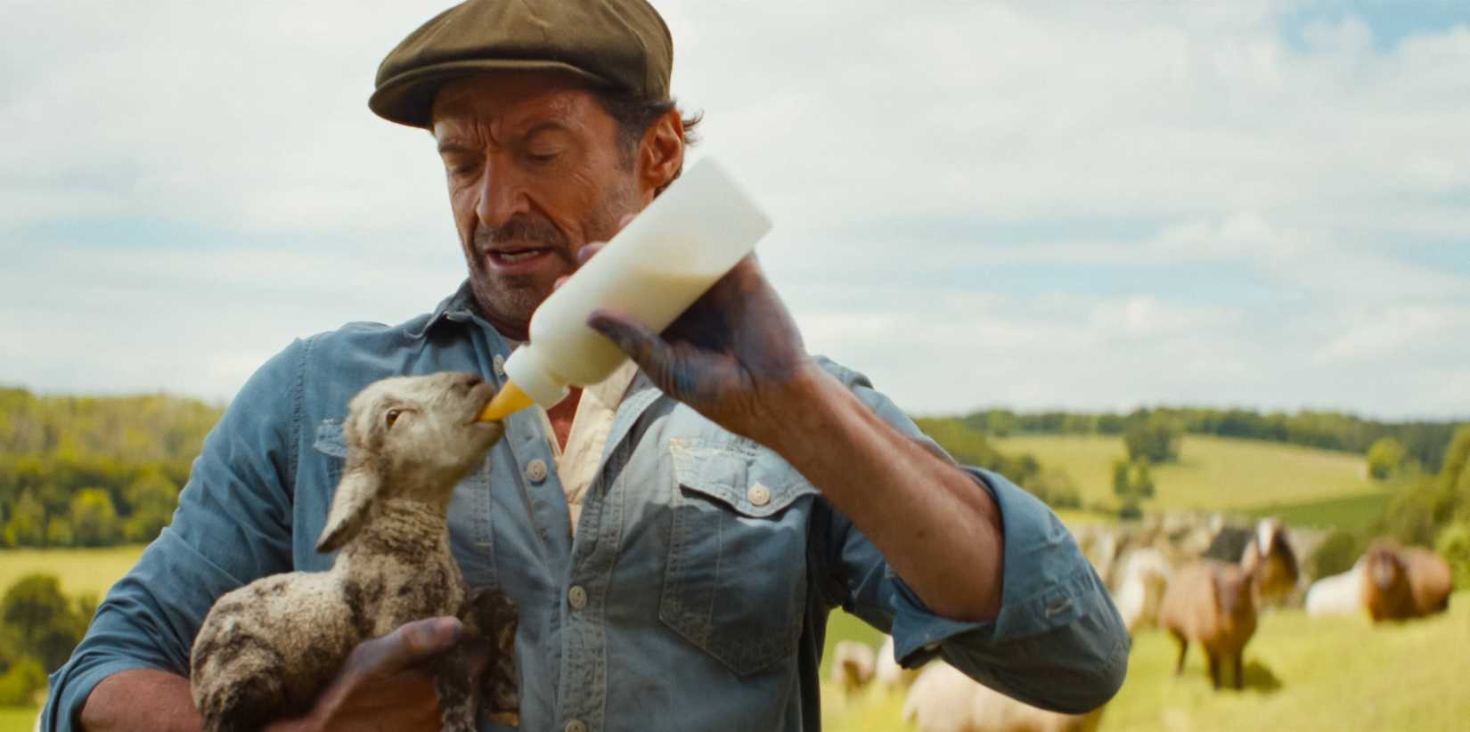 Hugh Jackman feeds a kid goat from a bottle in The Sheep Detectives.