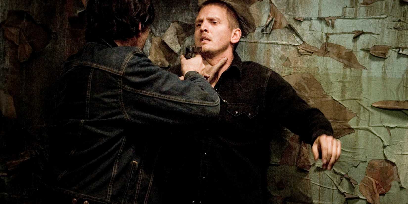 Um homem aponta arma para outro em Unknown